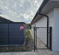 A family house on Ľadová Street in Miloslavov with a metal fence and a paved walkway.