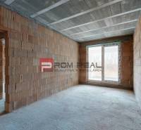 Unplastered room with a large window in a family house, ready for completion.
