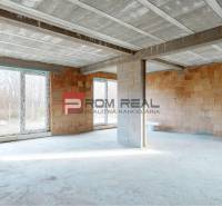 The interior of an unfinished family house with large windows and brick walls.