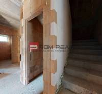A rough construction in a family house with a staircase and brick walls.