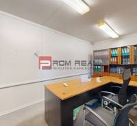 Office room with furniture, a chair, and a shelf with folders in a storage environment.