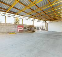 A spacious interior in a warehouse with a concrete floor and a metal roof.