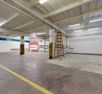 A warehouse space with white walls, a concrete floor, and yellow doors.