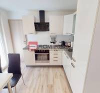 A kitchen in a 3-room apartment with white cabinets and a dining table.