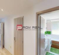 A hallway in a 3-room apartment with doors to the bathroom and a room, light wooden floors.
