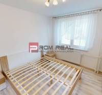 A bright bedroom in a 3-room apartment with a bed and nightstands, white walls.