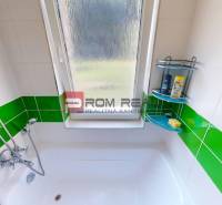 A bathroom in a 3-room apartment with green tiles, a bathtub, and a shower faucet.