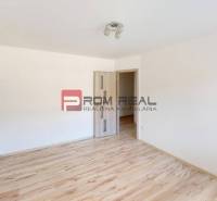 An empty room with wooden flooring and light walls in a 3-room apartment.