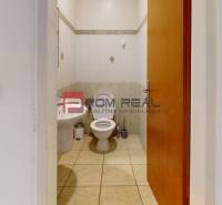 A restroom in an office space with basic fixtures and wall tiles.