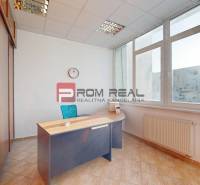 Office with a desk, shelves, and a large window, light streaming in.