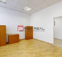 Offices with wooden furniture and tiles, light walls, entrance through open doors.