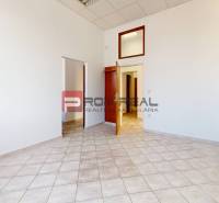 An office with white walls, ceramic flooring, and wooden doors.