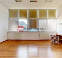 A few white walls, wooden floor, and windows with blinds, office furnishings.