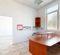 Offices with a large window, wooden furniture, and tiled floor.