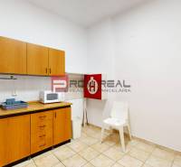 Offices with a kitchenette, wooden cabinets, microwave, chair, and sink.