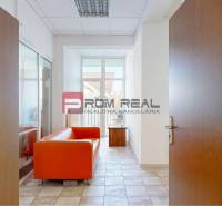 A narrow hallway in offices with an orange sofa and a glass wall.
