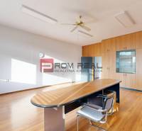Office with wooden furniture and desk, spacious interior, window, ceiling fan.