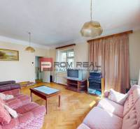 Living room in a family house with light walls, a couch, and a television.