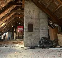 Attic with a wooden structure under the roof in a family house, full of clutter.