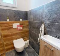 A bathroom with wood and stone tiles in a 3-room apartment, with a small sink.