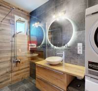A bathroom in a 3-room apartment with wooden paneling, a sink, and an AEG washing machine.