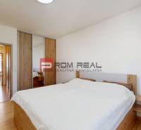 Bedroom in a 3-room apartment with wooden floors and a bed with a white throw.