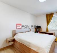 A bedroom with light walls and a wooden bed in a 3-room apartment.