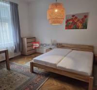 A bedroom with a wooden bed, a desk, and light decor in a 2-room apartment.