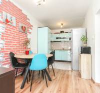 A kitchen in a 3-room apartment with a backdrop decor and a dining table.