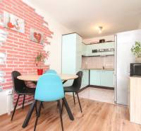A kitchen in a 3-room apartment with wooden flooring and brick decoration on the wall.