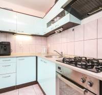 The kitchen of a three-room apartment with a gas stove and light kitchen cabinets.