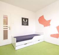A children's room with a white bed and a green carpet in a 3-room apartment.