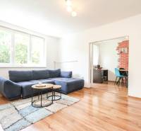 Living room with a sofa and tables in a 3-room apartment, with a view of the workspace through the opening.