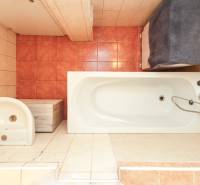 A bathroom with a bathtub and a sink in a 3-room apartment, tiles in warm shades.