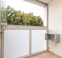 A balcony in a 3-room apartment with a view of the trees, which is part of the property.