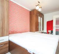A bedroom in a 3-room apartment with wooden wardrobes and a brick wall.