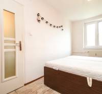 Bedroom in a 3-room apartment with a bed, window, and wooden floor.