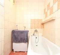 A bathroom in a 3-room apartment with a bathtub and a washing machine, tiled.