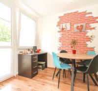 Dining area in a 3-room apartment with a round table and a decorative brick wall.