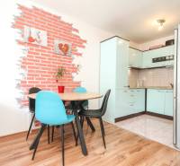 Dining area with a table and chairs in a 3-room apartment, with a wall featuring a brick pattern.