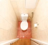 A toilet with tiles and toilet paper in a 3-room apartment.