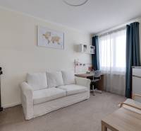 A room in a 3-room apartment with a sofa, a desk, and a television.