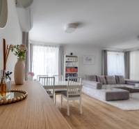 A bright interior of a 3-room apartment with a sofa, dining area, and decorations on a wooden table.