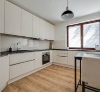 A kitchen in a 3-room apartment with wooden flooring and white cabinets.