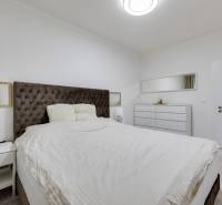 Bedroom with a large bed, nightstand, and dresser in a 3-room apartment.
