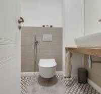 A bathroom with a wall-hung toilet and sink in a 3-room apartment with geometric tiles.
