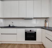 A kitchen in a 3-room apartment with white cabinets and a dark countertop.