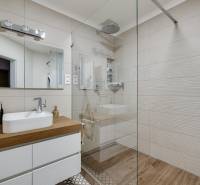 A bathroom with a white sink on a wooden countertop and a large mirror, 3-room apartment.