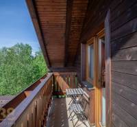Balcony with a table and chairs in a Holiday Apartment with a view of the trees in the High Tatras.