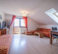 Recreational apartment with an orange sofa and a dining table under a skylight.